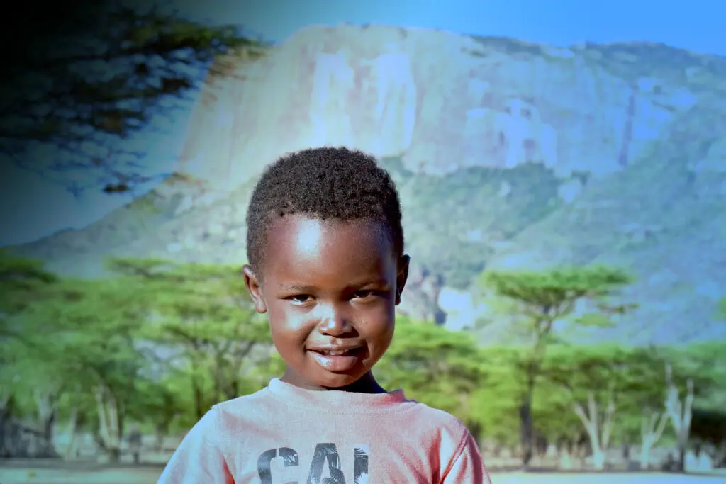 A photograph of a kid with a mountain range in the background