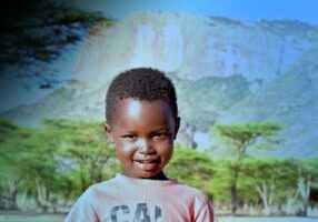 A photograph of a kid with a mountain range in the background